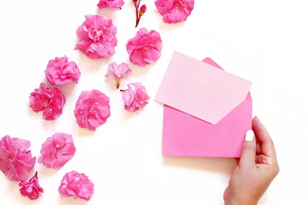 Mão Mantém Envelope Rosa Perto Flores Cor Rosa Sobre Fundo — Fotografia de Stock