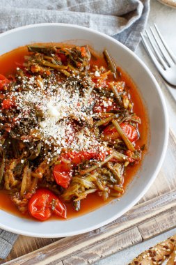 Sağlıklı sotelenmiş yeşil cicory ve üzerinde caccioricotta peyniri olan domatesler 