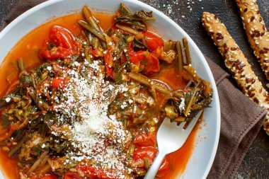 Sağlıklı sotelenmiş yeşil cicory ve üzerinde caccioricotta peyniri olan domatesler.