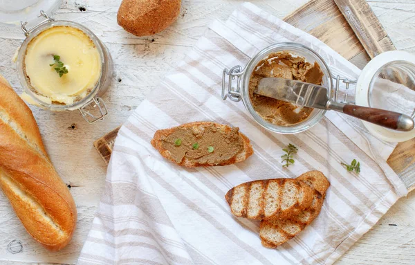 Ev yapımı ciğer ezmeli sandviçler ve masada bir kavanoz börek.