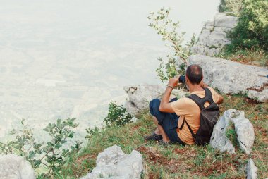 Güneşli bir günde dağlarda cep telefonuyla fotoğraf çeken adamlar.