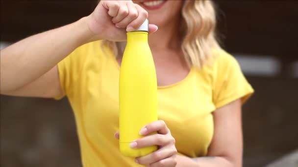 Close up of women in yellow t-shirt , holding yellow reusable steel bottle — Stock Video