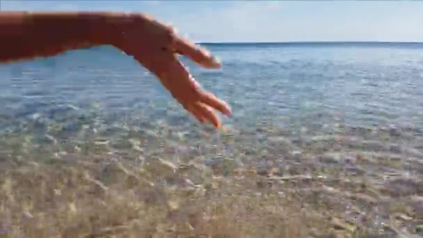 Lähikuva naisten käsi koskettaa merivettä — kuvapankkivideo