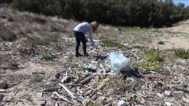 Plastik plaj bölgesini temizleyen genç bir kadın. — Stok video