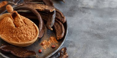 Kuru keçiboynuzu kapsülleri ve pudra Gri bir masaya yakın