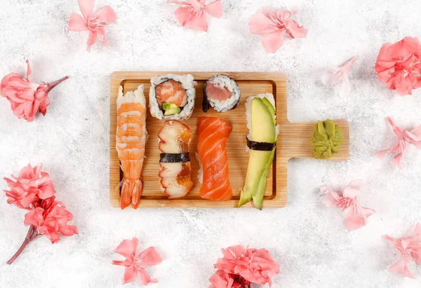 Sushi设置Nigiri和寿司滚动在Awooden板之间的花卉顶部视图 — 图库照片