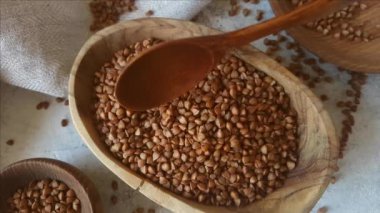 Kaşıkla bir kasede çiğ karabuğday taneleri.