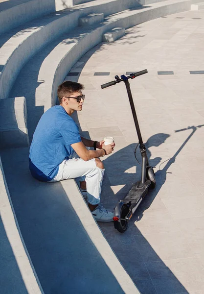 Joven Hombre Caucásico Sentado Aire Libre Cerca Scooter Eléctrico Beber — Foto de Stock