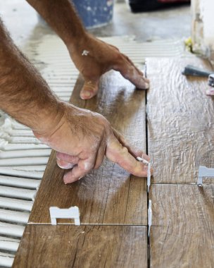 Son sınıflar seramik fayansları yapıştırıcı ile hazırlanmış bir evin zeminine yerleştiriyorlar. Bir binanın inşaatında ya da yenilenmesinde çalışan bir zanaatçı, DIY ev imalatçıları