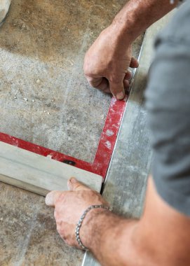 Marangoz fayanstan önce evin zeminindeki açıları ölçüyor. Eller yakın. Ev iç dekorasyonu. Yeni bir binanın inşaatı 