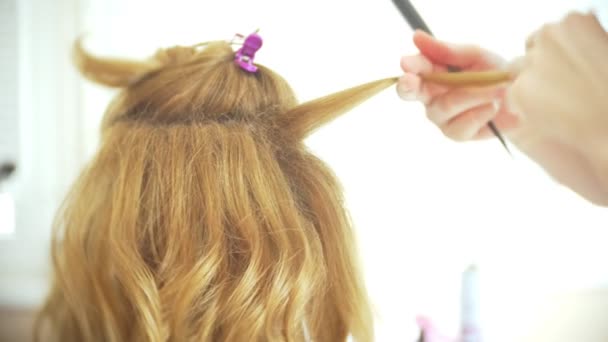Cabeleireiro faz um cachos para uma menina, usando o estilo de cabelo. Cabeleireiro no trabalho. 4k — Vídeo de Stock