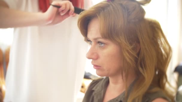 Saç stilisti bir kıvırcık saç şekillendirme kullanan bir kız için yapar. Kuaför iş başında. 4k — Stok video