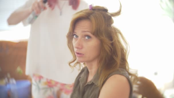 Στυλίστας μαλλιά κάνει μια μπούκλες για ένα κορίτσι, χρησιμοποιώντας styling μαλλιών. Κομμωτήριο στο χώρο εργασίας. 4k — Αρχείο Βίντεο