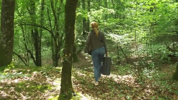 Meisje, wandelingen door de bossen met een zware zwarte koffer. 4k, slow-motion-video schieten, steadicam schot. — Stockvideo