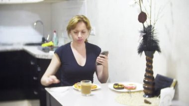 kadın mutfakta evde pizza yiyor ve onun smartphone, 4 k, kullanarak arka plan bulanıklık