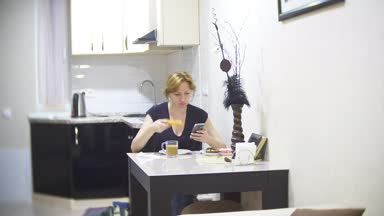 kadın mutfakta evde pizza yiyor ve onun smartphone, 4 k, kullanarak arka plan bulanıklık