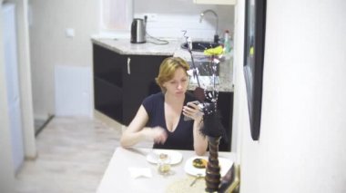 kadın mutfakta evde pizza yiyor ve onun smartphone, 4 k, kullanarak arka plan bulanıklık