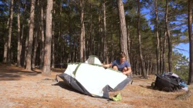 erkek bir turist bir çadır pine Grove dik kıyı kıyı kenarında deniz manzarası muhteşem bir görünüm ile düzenler. 4k.
