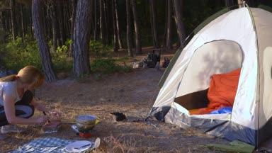 turistler yanında deniz manzarası muhteşem manzaralı pine Grove dik bir sahil kenarında bir çadır kamp yemek yeme, mutlu bir aile. 4k.