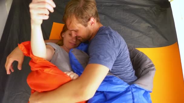 クローズ アップ。かわいいカップルの寝袋に横たわっているテントの中を抱いて、彼らは浮気し、キス、4 k. — ストック動画