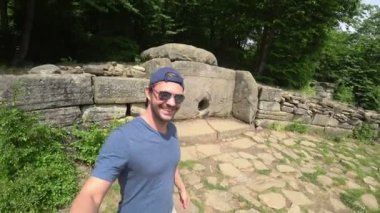 Bir turist bir eylem kamera ile Dolmen inceliyor. Dolmen ormanın içinde. turistler antik Dolmen keşfetmek