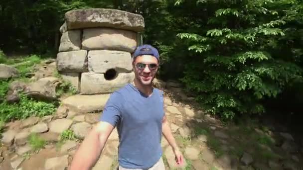 Um turista com uma câmera de ação examina dolmens. Dolmen na floresta. turistas explorar os antigos dolmens — Vídeo de Stock