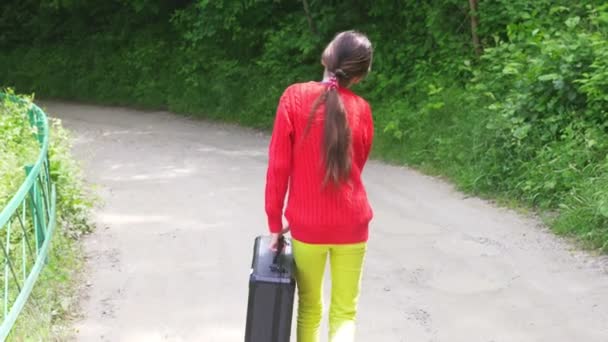 Girl, walks through the woods with a heavy black suitcase. 4k, slow-motion shooting, steadicam shot. — Stock Video