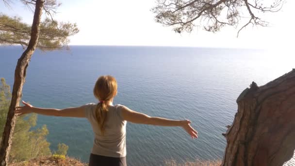 Donna corridore fitness sulla cima felice e celebrando il successo. la donna gode della vista del mare dalla montagna, alza le mani e sente la libertà e il respiro del vento. 4k, rallentatore — Video Stock