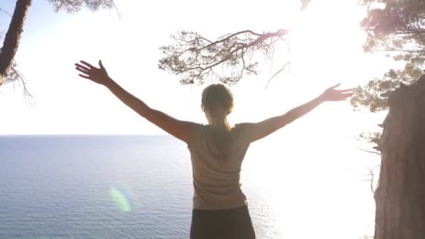 Mulher corredor fitness no topo feliz e celebrando o sucesso. a mulher desfruta da vista do mar a partir da montanha, levanta as mãos e sente a liberdade e o sopro do vento. 4k, câmera lenta — Vídeo de Stock