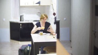 kadın mutfakta evde pizza yiyor ve onun smartphone, 4 k, kullanarak arka plan bulanıklık