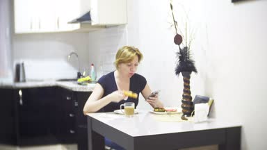 kadın mutfakta evde pizza yiyor ve onun smartphone, 4 k, kullanarak arka plan bulanıklık