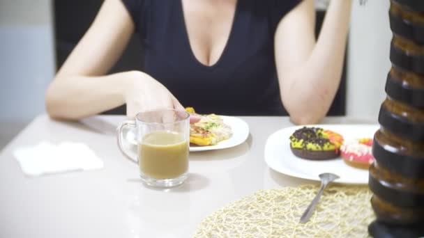 Mujer está comiendo pizza en la cocina en casa y utilizando su teléfono inteligente, 4k, desenfoque de fondo — Vídeos de Stock