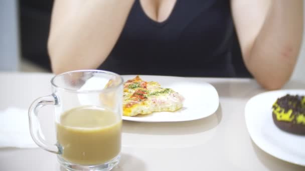 女性は自宅のキッチンでピザを食べているし、彼女のスマート フォンは、4 k を使用して背景をぼかす — ストック動画