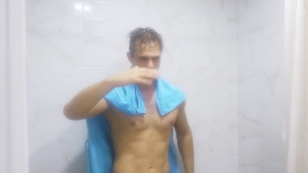 Νεαρός όμορφος μυώδης άνδρας μετά το ντους στο μπάνιο. Έβαλε σε μια πετσέτα στους ώμους του, απεικονίζοντας μια υπεράνθρωπος, 4k — Αρχείο Βίντεο