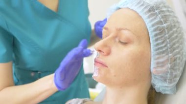 Güzellik uzmanı Doktor hastanın kontur Plasti prosedürü önce yüzünde anestezi krem uygulanır. 4k