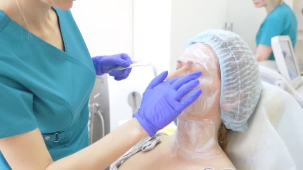 Kosmetolog läkaren gäller narkos grädde på framsidan av patienten innan förfarandet av contour plasty. 4k — Stockvideo