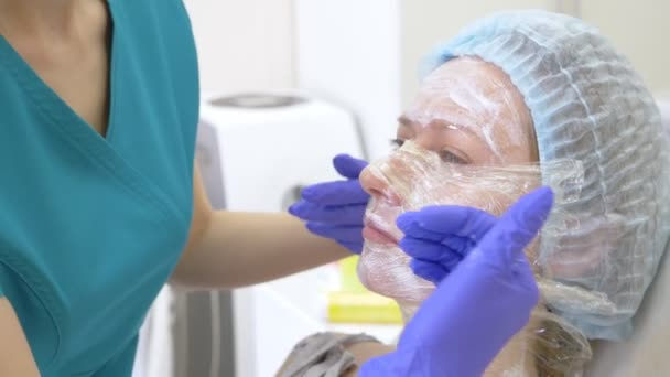 Kosmetolog läkaren gäller narkos grädde på framsidan av patienten innan förfarandet av contour plasty. 4k — Stockvideo