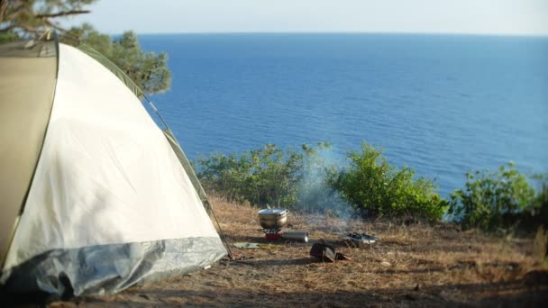 Eine Melone und ein Einweggrill. Kochen neben einem Zelt am Rande einer steilen Küste in einem Pinienhain mit herrlichem Blick auf die Meereslandschaft. 4k. — Stockvideo