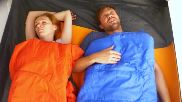Primer plano. Una linda pareja abrazándose dentro de una tienda de campaña acostada en sacos de dormir, coquetean y se besan, 4k . — Vídeos de Stock