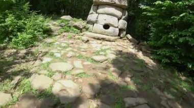 Bir turist bir eylem kamera ile Dolmen inceliyor. Dolmen ormanın içinde. turistler antik Dolmen keşfetmek