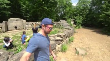 Bir turist bir eylem kamera ile Dolmen inceliyor. Dolmen ormanın içinde. turistler antik Dolmen keşfetmek