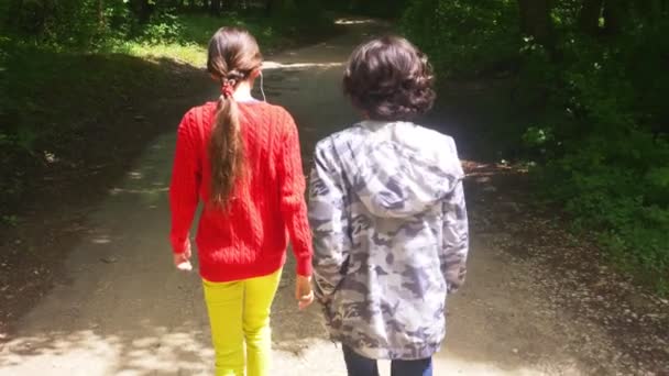 Ein Junge und ein Mädchen, die im Wald unterwegs waren, schossen von hinten auf einen Stamm. 4k, Zeitlupe — Stockvideo