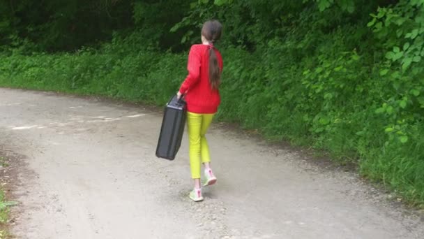 女の子、重い黒のスーツケースと森の中を歩きます。4 k、スローモーション撮影、ステディカム ショット. — ストック動画
