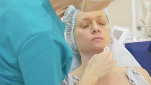 De schoonheidsspecialist-arts is verdoving crème op het gezicht van de patiënt vóór de procedure van contour plastie van toepassing. 4k — Stockvideo