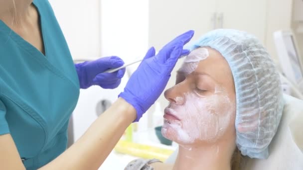 Der Arzt des Kosmetologen trägt vor dem Eingriff der Konturplastik eine Narkosecreme auf das Gesicht des Patienten auf. 4k — Stockvideo