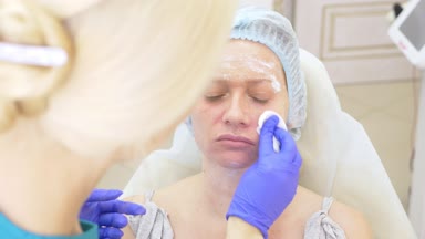 Güzellik uzmanı Doktor hastanın kontur Plasti prosedürü önce yüzünde anestezi krem uygulanır. 4k