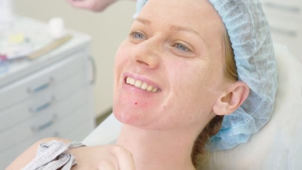 The woman looks at her face in the mirror after the procedure in the doctors office of the beautician. 4k. — Stock Video