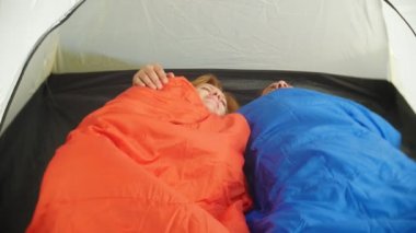 Portre. Uyku tulumları içinde yalan bir çadır içinde sarılma tatlı bir çift onlar flört ve öpücük, 4k.