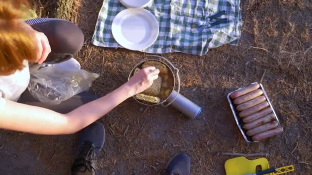 休憩、女性では、パイン グローブに急な海岸線の雄大な海の景色との端にテントの横に料理します。4 k. — ストック動画