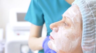 Güzellik uzmanı Doktor hastanın kontur Plasti prosedürü önce yüzünde anestezi krem uygulanır. 4k